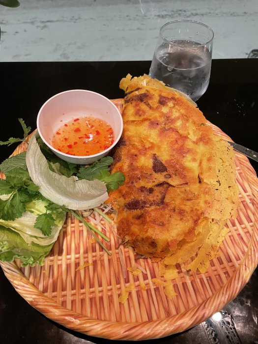 Vietnamesisk Bánh Xèo, örtig sallad, fisksås, vatten i glas, matplacering, asiatiska smaker, traditionell måltid, krispig pannkaka.