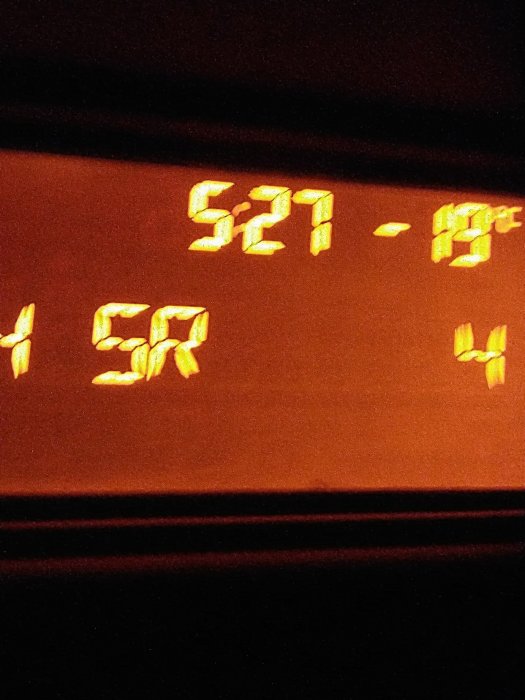 Digital display showing time "5:21" and temperature "-19°C". Possibly a car dashboard at night.