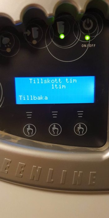 Maskinpanel med blå skärm, text "Tillkott. tid 1tim", knappar, två gröna lampor, "EEN LINE" märkning.