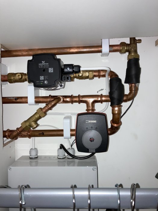 Installation av VVS med kopparledningar, cirkulationspump, och värmeregulator under tak, inomhus.