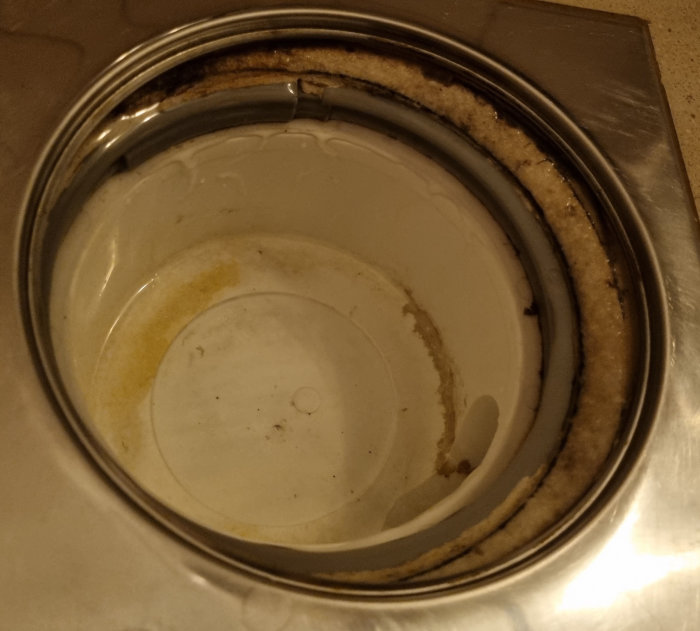 Ett smutsigt, rostfritt stålfat med bruna fläckar och ringar, behöver rengöras.