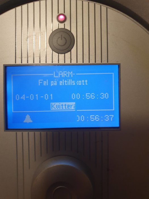 Panel med LED, text "LARM Fel på eltilsott", tid, knappar. Anordning verkar visa ett elrelaterat problem.