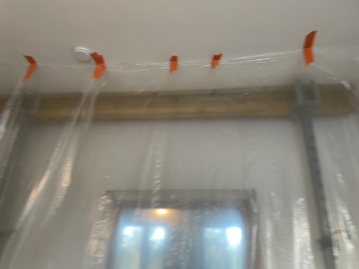 Oskarpt byggarbetsutrymme med plastfolie och orange tejp.