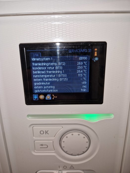 Display med temperaturdata och status för uppvärmningssystem, omgiven av knappar, grönt statusljus tänds.