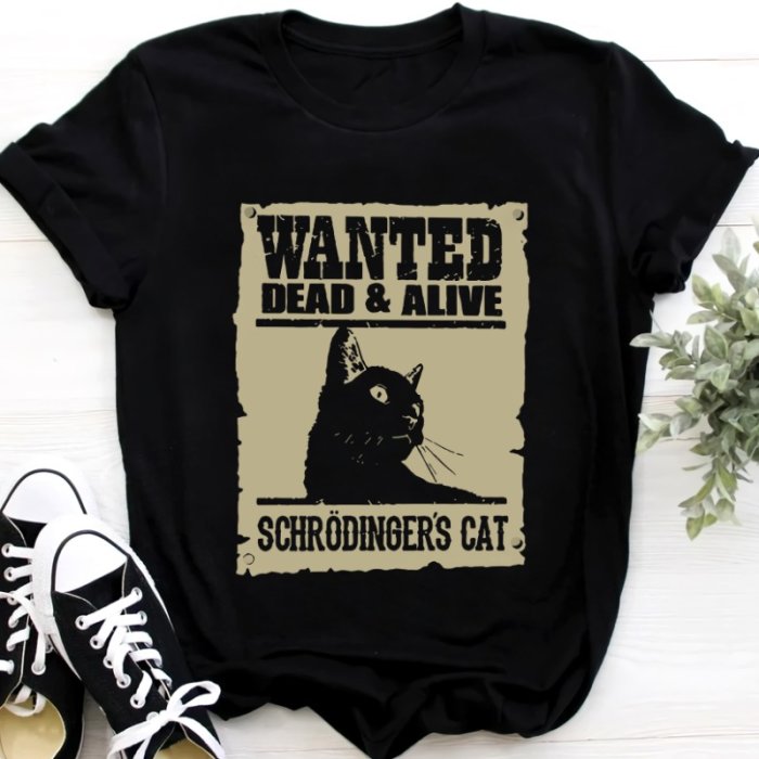 Svart t-shirt med "Wanted Dead & Alive - Schrödinger's Cat" tryck, ordspel, kvantfysikreferens, på en yta.