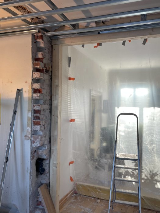 Renoveringsarbete pågår, metalldetaljer, murbruk, stegpall, genomskinlig plast, gipsplattor, isoleringsmaterial, träreglar.