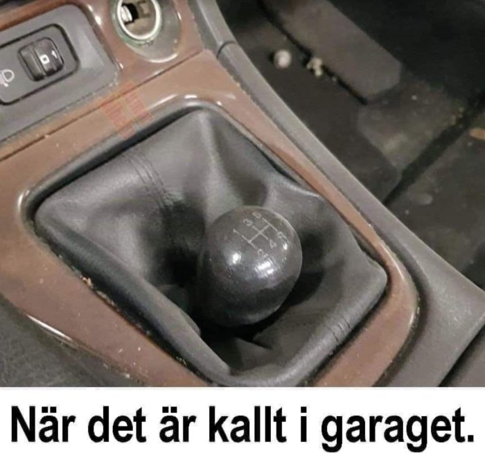 Växelspak i bil med skiftmönster i kallt garage; humoristisk bildtext på svenska.