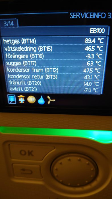 Digital display med temperaturvärden, knappar under, grönt sken ovanför, möjligen en värmepump eller termostat, serviceinformation.