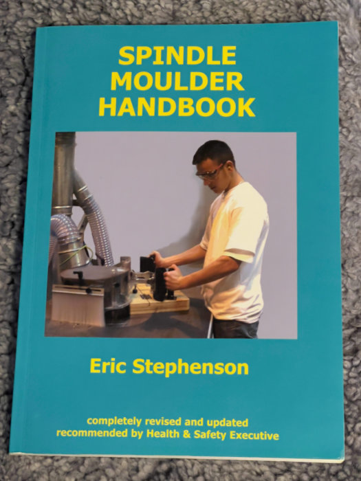 Bok med titeln "SPINDLE MOULDER HANDBOOK" av Eric Stephenson, träarbete, rekommenderad av hälsomyndighet, person använder maskin.