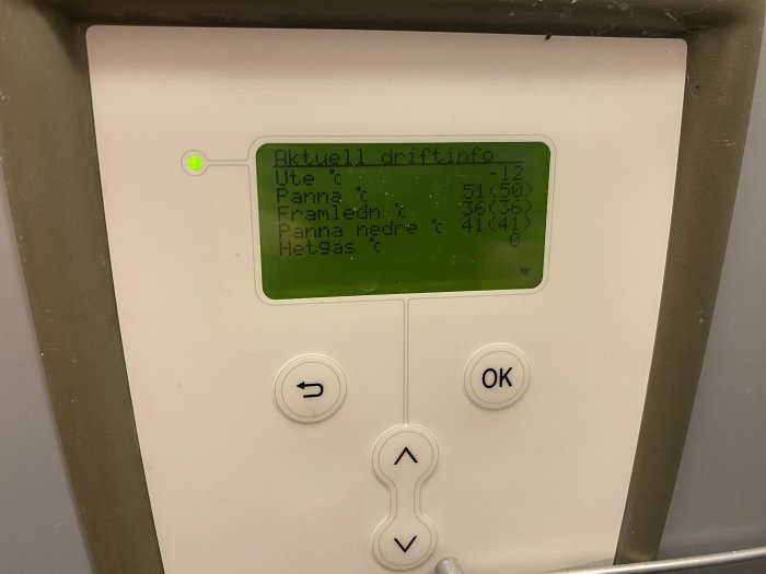 Digital skärm med driftinformation, knappar för navigering, på en värmepump eller liknande enhet.