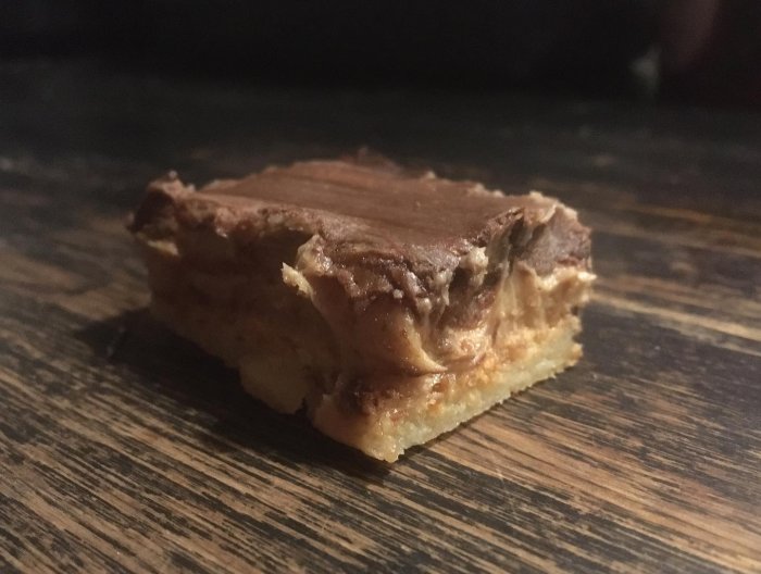 Ett stycke choklad- och kolakaka på träbord. Frestande dessert med rika lager.