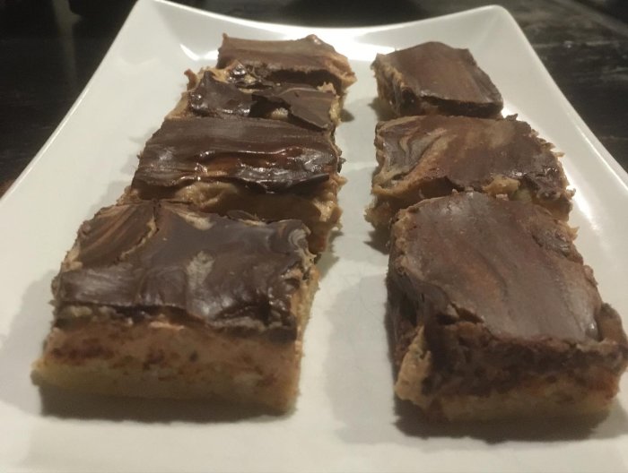 Kakor med chokladöverdrag på en vit rektangulär tallrik, ser hemmagjorda ut, möjligtvis efterrätt eller fika.