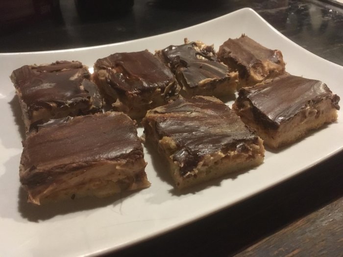 Ett fat med skurna chokladglaserade bakverk, möjligen hemgjorda, på en mörk yta.