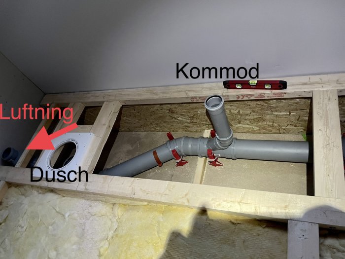 Installation av avloppsrör, ventilation och duschbas i byggfas, anmärkt med röd text och vattenpass.