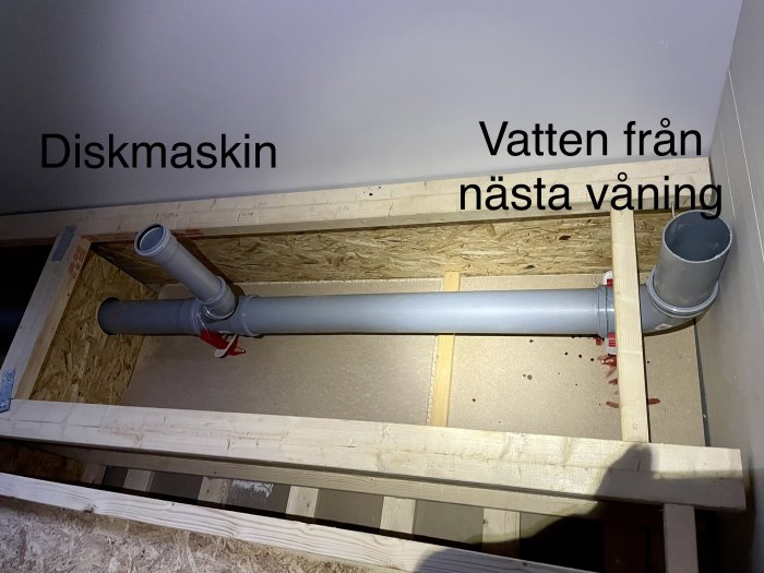 Installation av rör under golv; märkning för diskmaskin och vattenledning; oavslutad konstruktion; trästomme och OSB-skivor.