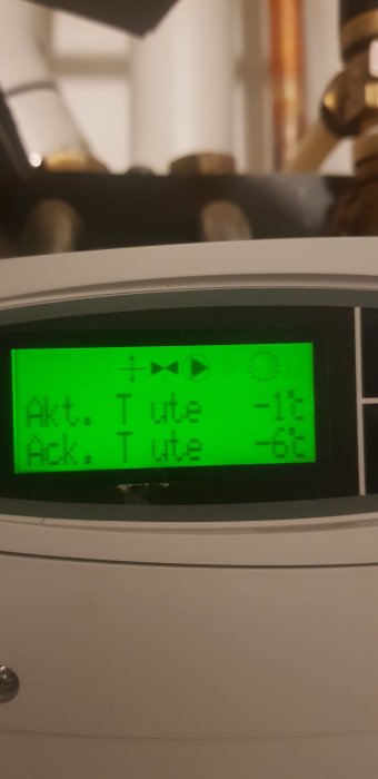 Digital display visar temperaturer: nuvarande utomhus -1°C, ackumulerad utomhus -6°C. Grönt bakgrundsbelysning, suddig bakgrund.