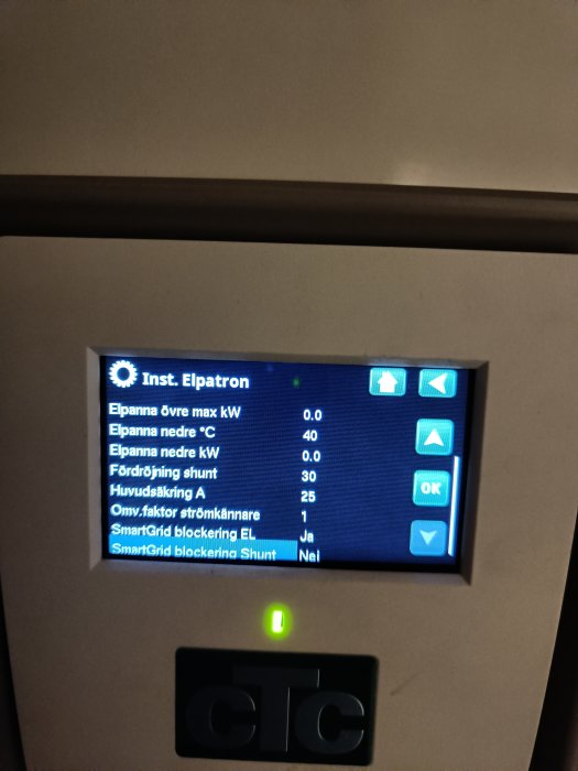 Digital skärm med tekniska inställningar för elpanna och energihantering, blå bakgrund, grönt OK och pilknappar.
