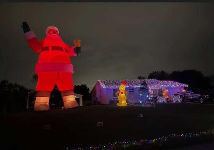 En stor uppblåsbar Jultomten och ljusdekorerat hus under kvällen.