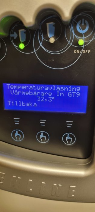 Digitalt display visar temperaturväxling, varmebärare in, grön lampa, knappar, tillbaka-meny, svensk text, maskinpanel.
