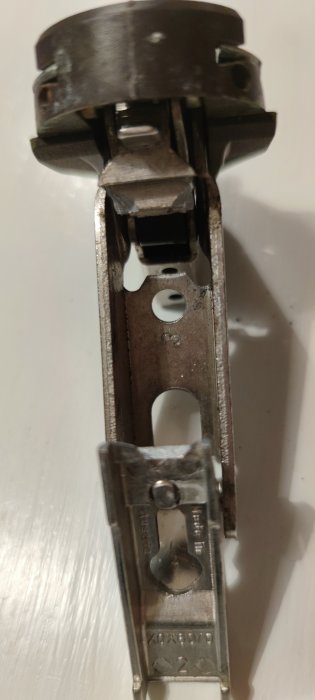 Verktyg, troligtvis en häftapparat eller klämmaskin, metallisk, använd, närbild, suddig bakgrund.