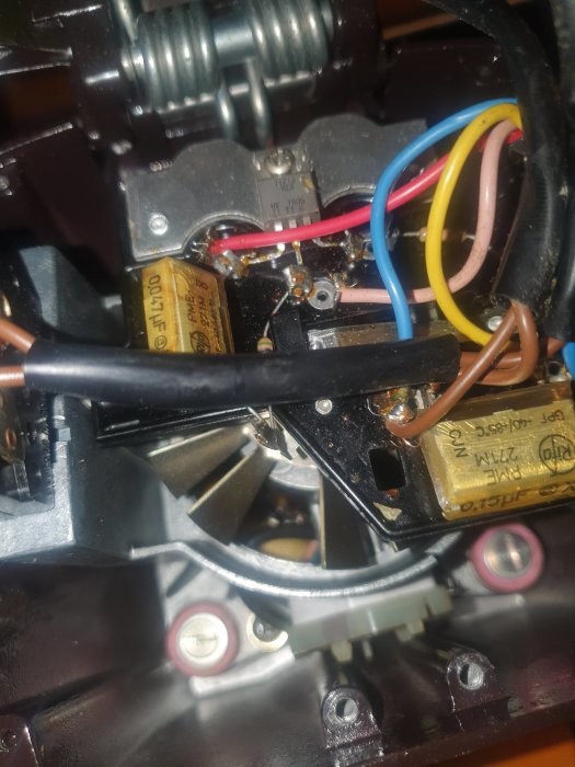 Elektriska komponenter, kondensatorer, trådar, skruvar inuti en apparat. Närbild på inre mekanik eller elektronik.