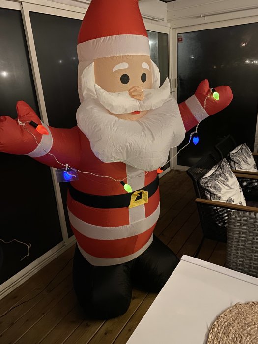 Uppblåsbar jultomte med randig tröja och ljusslinga utomhus på kvällen.