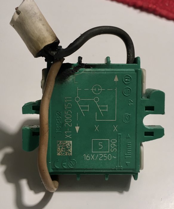 Bränt elektriskt komponent, grönt, med kablar och märkningar, potentiell brandrisk, brandskada, kondensator eller säkring.