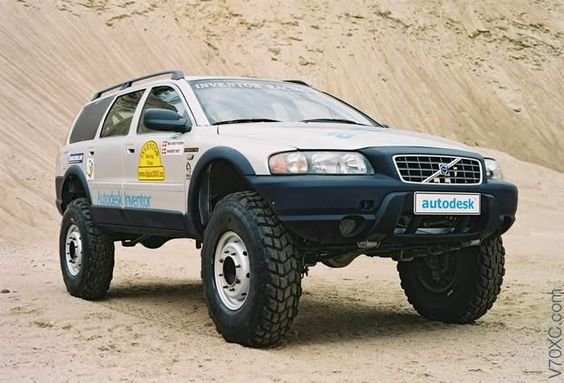 Modifierad SUV, stora terrängdäck, sponsrade dekaler, står på sand, Volvo, offroad-förberedd.