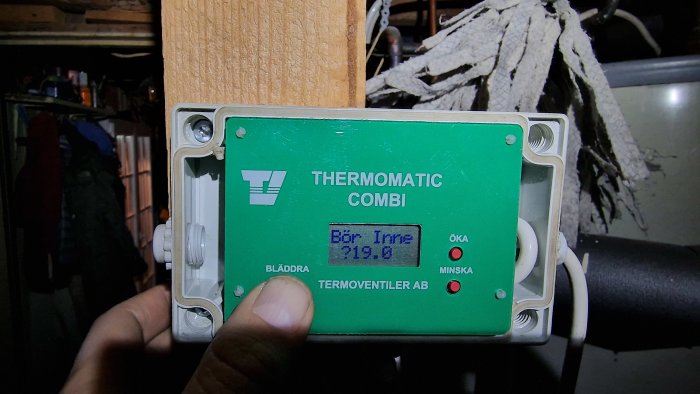 En grön termostat med visning av temperatur på 219,6 grader. Knappar för att öka eller minska.