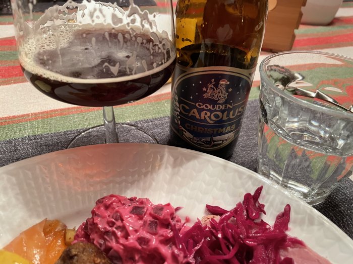 Julöl i glas, Gouden Carolus-flaska, vattenglas, julmat med rödkål på tallrik.