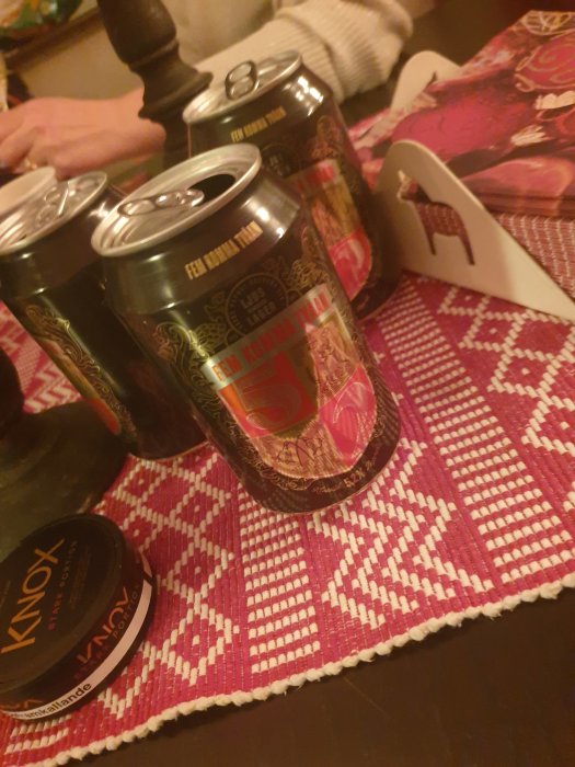 Tre ölburkar, snusdosa på rödvit rutig duk, del av en bordsbokhållare synlig.
