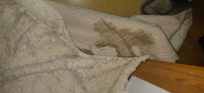 En matta och en handduk med smutsiga fläckar på ett trägolv i ett hem.