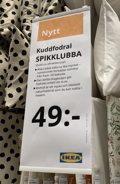 IKEA-skylt för kuddfodral "SPIKKLUBBA", svartvitt mönster, pris 49 kronor, heminredningsbutiksmiljö.