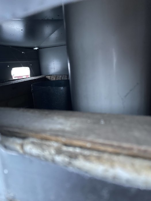 Oskarp bild inuti struktur, metallrör, öppning med ljusinsläpp, mörkt utrymme, industriell känsla.