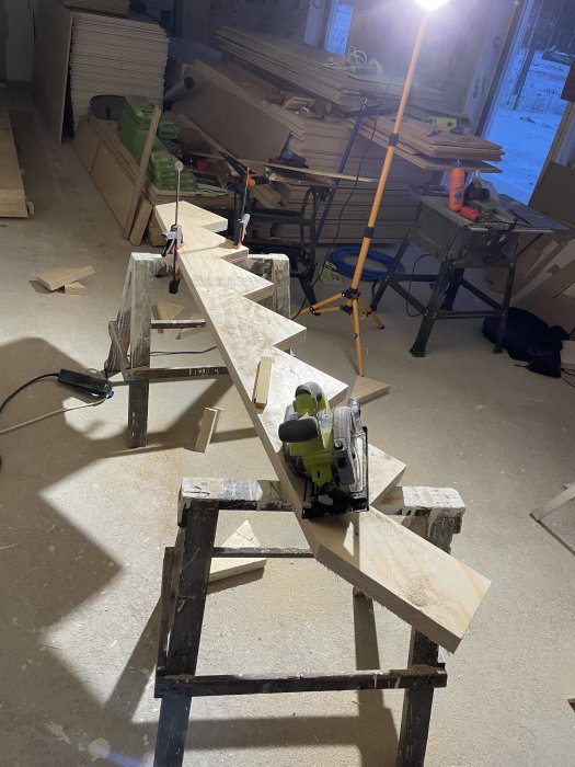 Verktyg och trämaterial i ett pågående snickeri- eller byggprojekt inne i en verkstad.