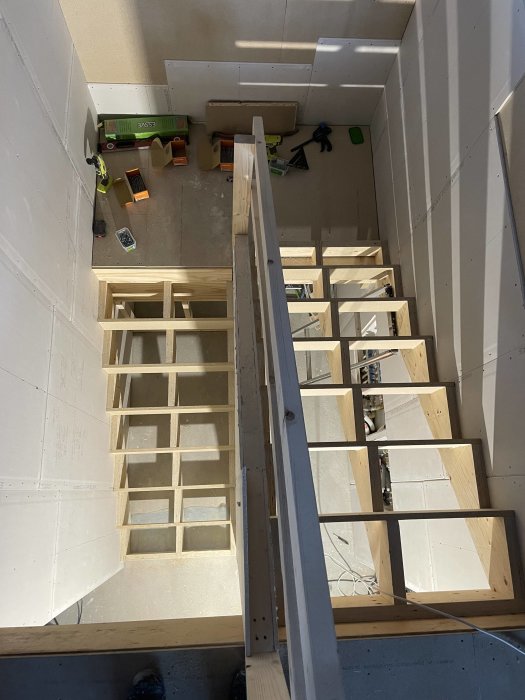 Trappkonstruktion i byggfas, verktyg och material synliga, oavslutat arbete, trästruktur, inhyst i en byggnad.