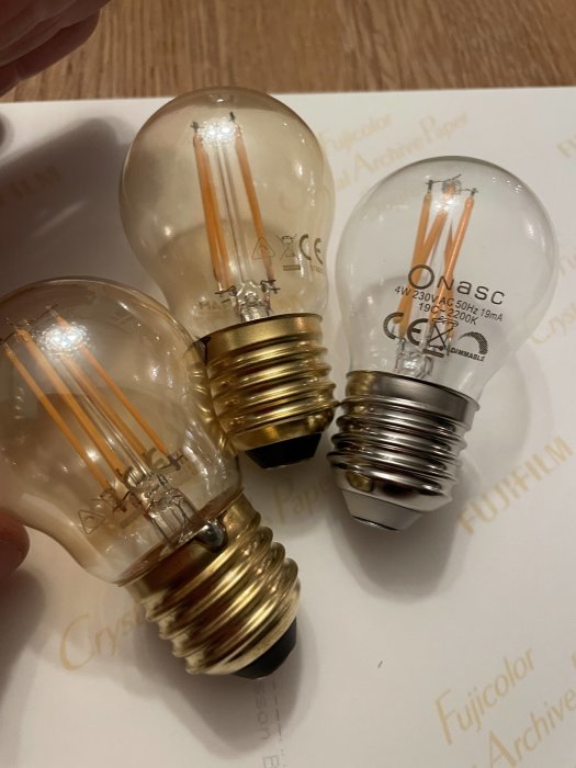 Tre LED-glödlampor med olika socklar på ett bord, inte tända.