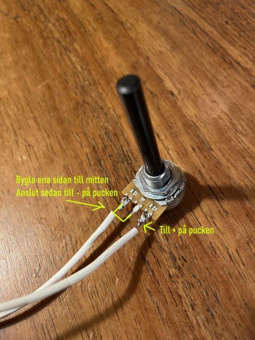 Potentiometer med lödda kablar och anvisningar på träunderlag.