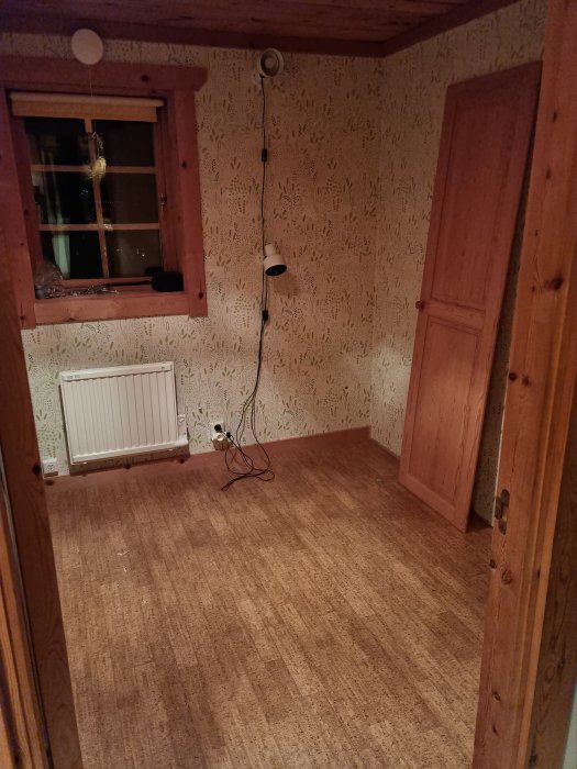 Tomt rum med trädetaljer, tapetväggar, fönster, lampa och radiator.