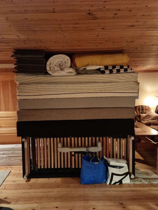 En hög med madrasser staplade på varandra ovanför en ribbotten med förvaring under i ett trärum.