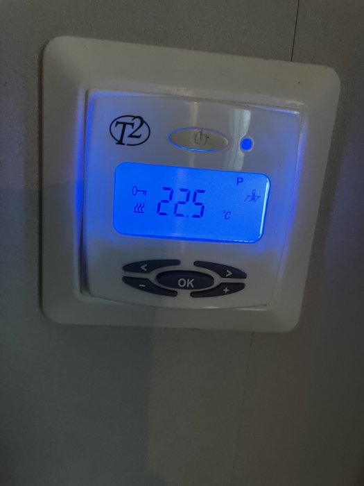 Digital termostat visar inomhustemperatur på 22,5 °C, omgivet av knappar för inställningar.