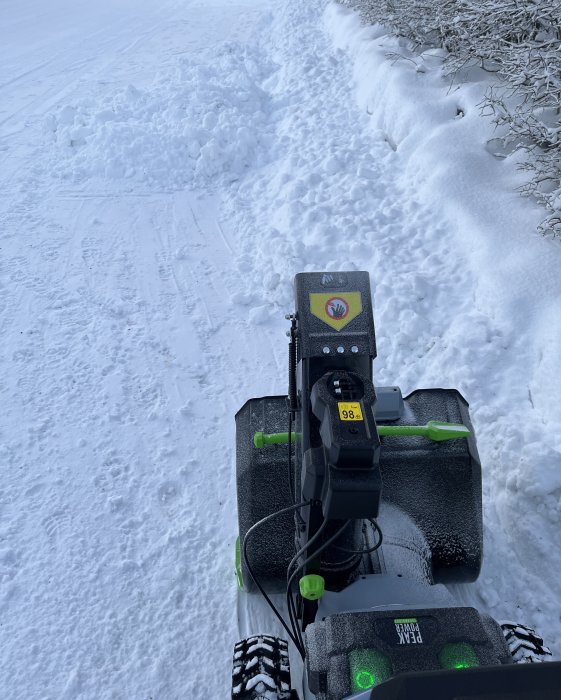 Snöslunga i arbete på snötäckt väg, snöhögar, vinterdag.