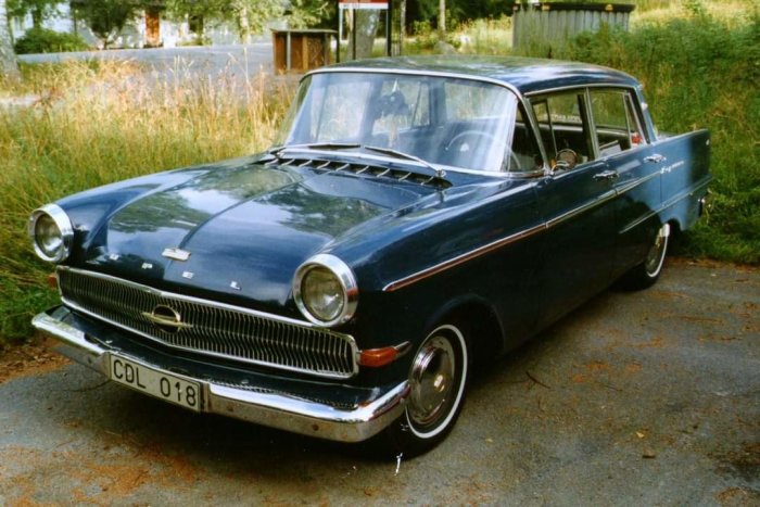 Klassisk blå Opel Rekord parkerad utomhus, kromdetaljer, vit sidorand, registreringsskylt synlig.