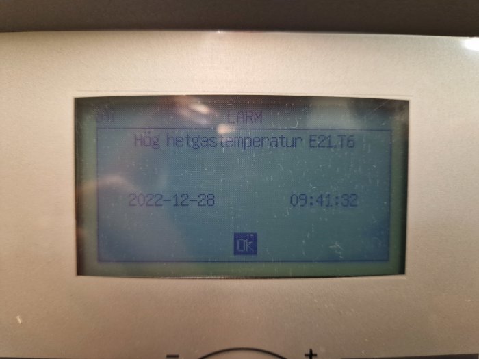 LCD-display med varningsmeddelande, "Hög nettasstemperatur E21.16", datum och tid synlig.