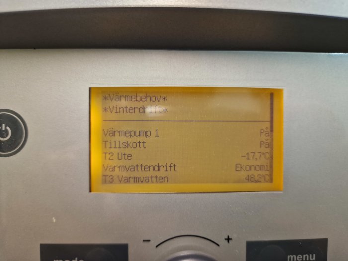 Digital display på en värmepump med temperaturinformation och driftlägen; innebär kallt klimat med aktivt värmebehov.