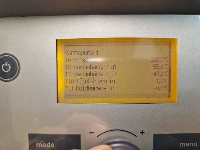 Digital display visar temperaturdata för värmepump: hetgås, varmvatten in/ut, kylvatten in/ut. Knappar för inställningar under.