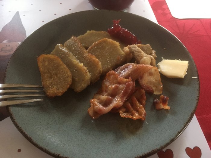 Ett fat med potatiskorv, stekt bacon, smörklick, och lingonsylt, traditionell svensk mat.