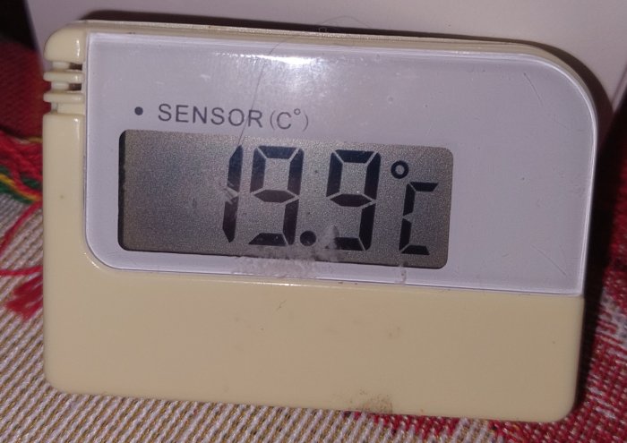 Digital temperaturmätare visar 19.9°C, liggande på en tygyta.