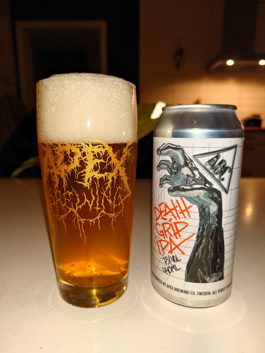 Ölglas med skum och burk med konstnärlig etikett, "Death Grip IPA", från Apex Brewing, Sverige.