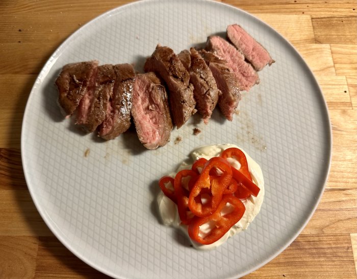 Upptagen tallrik med medium rare stek, gräddig sås och röd paprika.